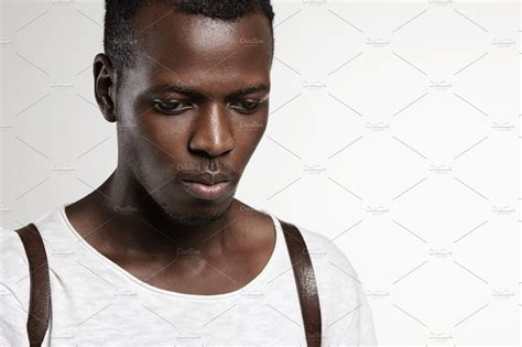 Portrait Of Good Looking Attractive Dark Skinned Male Model Wearing White T Shirt Looking Down