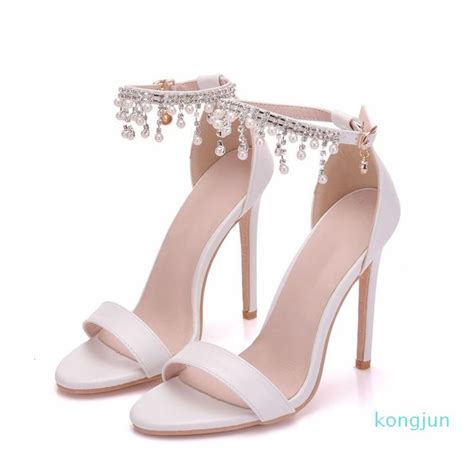 A Pair Of White High Heeled Shoes With Pearls On The Ankle And An Ankle