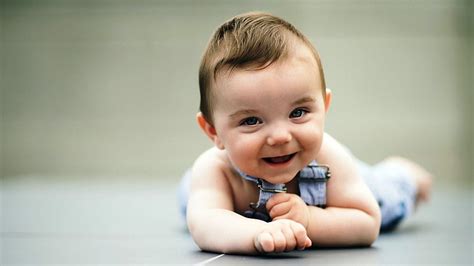 Smiley Cute Baby Is Lying Down On Floor Wearing Light Blue Dress In