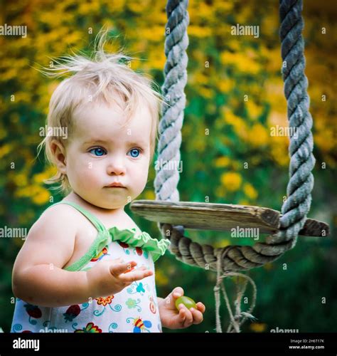 Cute Baby Girl 3 4 Year Old In The Garden Plays A Rustic Swing Stock