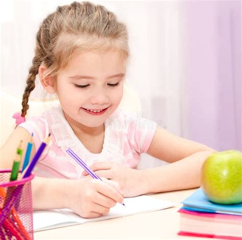 Cute Little Girl Is Writing At The Desk Stock Photo Image Of