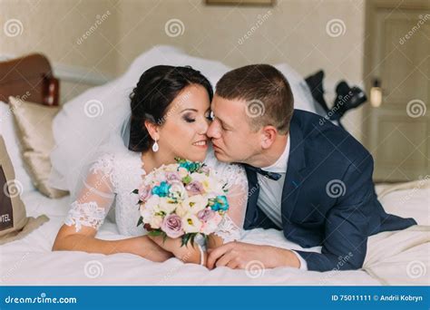Happy Bride And Groom Lay On Bed In Hotel Room After Wedding