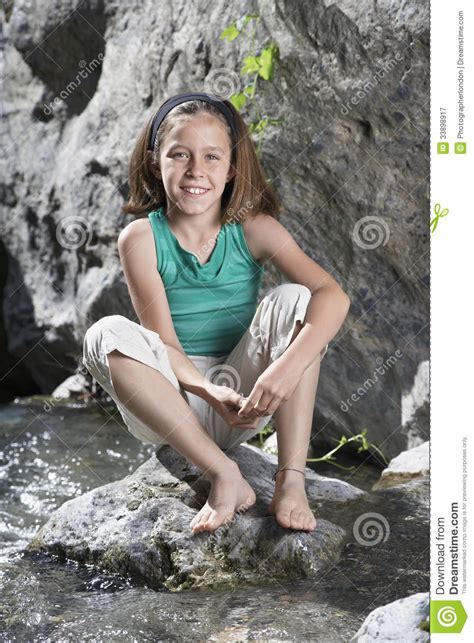 Portrait Of Girl Sitting On Rock By Stream Stock Image