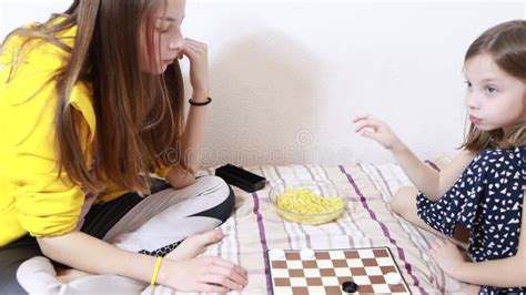 Two Sisters Play Checkers On The Bed And Eat French Fries Stock Footage