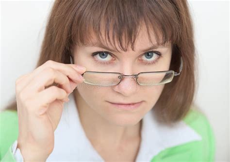 Strict Young Woman Looks At Us Over Eyeglasses Royalty Free Stock Image