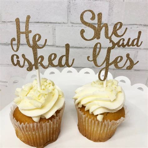 Two Cupcakes With White Frosting And Gold Sparklers On Top Are Sitting On A Cake Plate