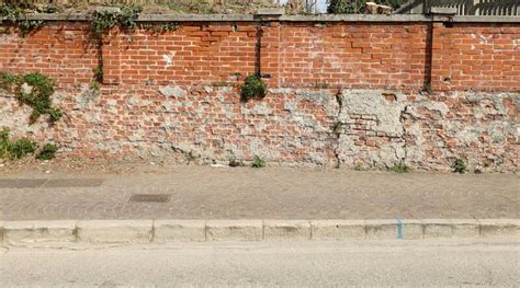 Grunge Boundary Brick Wall Porphyry Sidewalk And Asphalt Road In Front