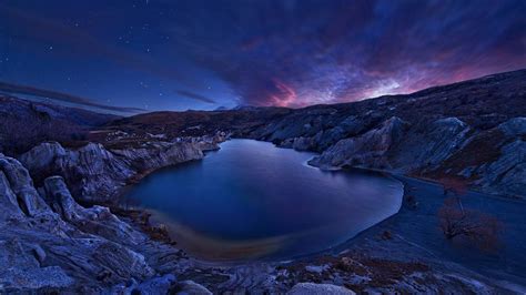 Lake Surrounded By Stones Rocks Under Starry Blue Sky During Nighttime