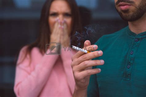 royalty free image passive smoking man smoking cigarette near woman covering her face from