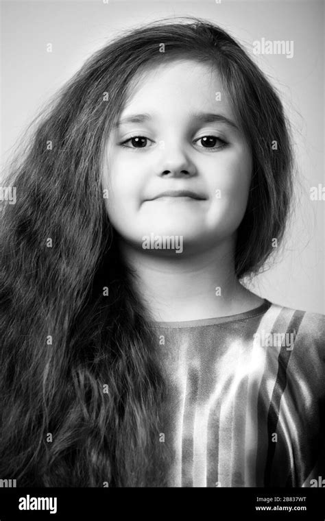 Portrait Of Small Positive Girl With Long Brown Hair Over Dar Grey Background Fashion And