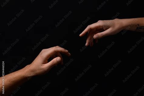Male And Female Hands Reaching Out To Each Other On Dark Background