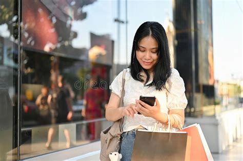 Asian Woman Using Smartphone Walking Along Of The Shopping Mall With