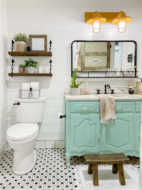 A cozy farmhouse bathroom with a serenity blue vanity, a tub, a large mirror and black fixtures for a more dramatic look. vintage dresser to bathroom vanity - Lolly Jane