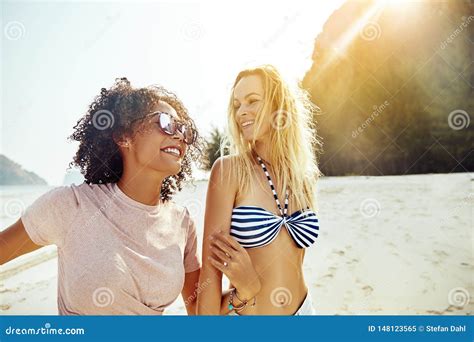 Two Women Laughing While Walking Together Along A Sandy Beach Stock Image Image Of Girls