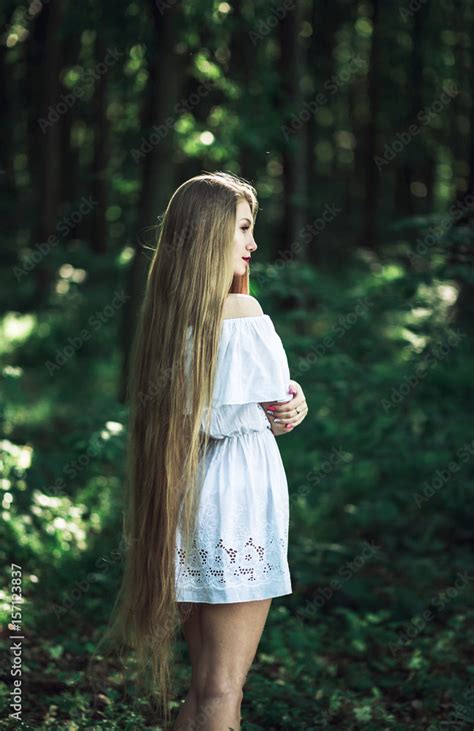 A Young Girl In White Dress With Long Blonde Hair Standing In The Woods