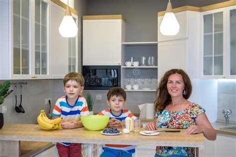 La Joven Madre Y Sus Dos Hijos En La Cocina Horneando Galletas Imagen