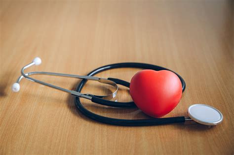 Black Doctor Stethoscope And Stress Ball In Heart Shape On Wooden Floor