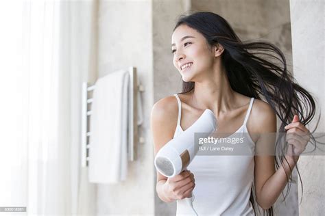 Young Woman Drying Her Hair With A Hair Dryer Photo Getty Images