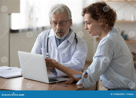 Serious Mature Doctor Showing Checkup Result On Laptop To Patient Stock Image Image Of Explain