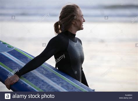 Female Surfer In Wet Suit Holding Surfboard On Beach Stock Photo Alamy