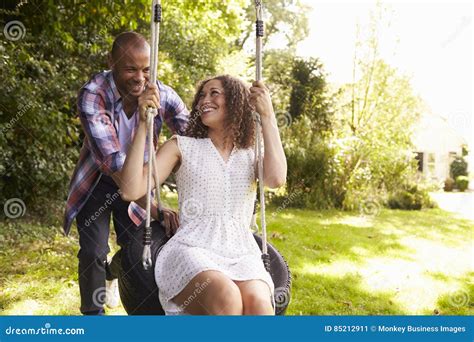 Man Pushing Woman On Tire Swing In Garden Stock Image Image Of Copy England