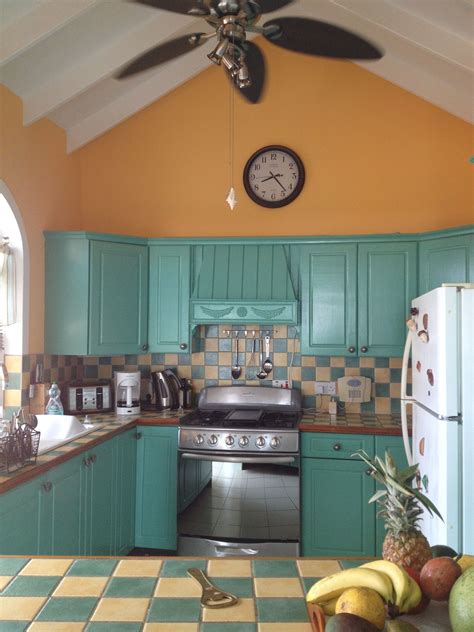 A Kitchen With Green Cabinets And A Clock On The Wall Above The Stove