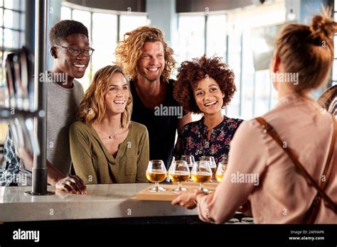 Waitress Serving Group Of Friends Beer Tasting In Bar Stock Photo Alamy