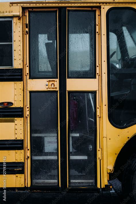 Close Up Of A Yellow School Bus Door With Blurred Windows Stock Photo