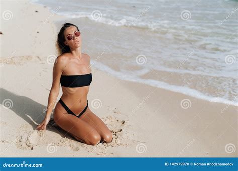 Sensual Tanned Girl In Swimsuit And Sunglasses Posing On White Sand