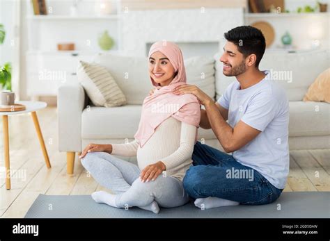 Amoroso Marido árabe Masajeando Los Hombros De Su Mujer Embarazada En Casa Sentados Juntos En