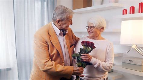 old man surprising his wife with bouquet of red roses anniversary birthday or valentines day
