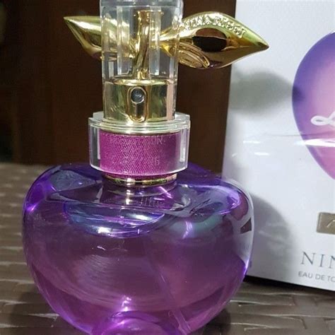 A Purple And Gold Perfume Bottle Sitting On Top Of A Table