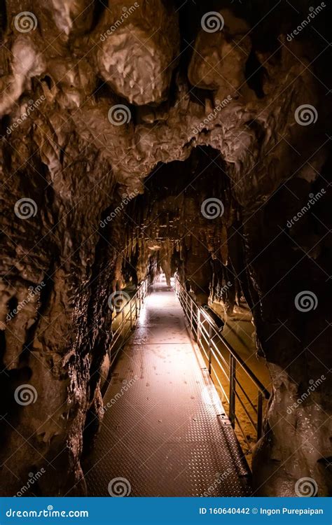 Trail Inside A Dark And Damp Cave There Are Lighting Attached Along