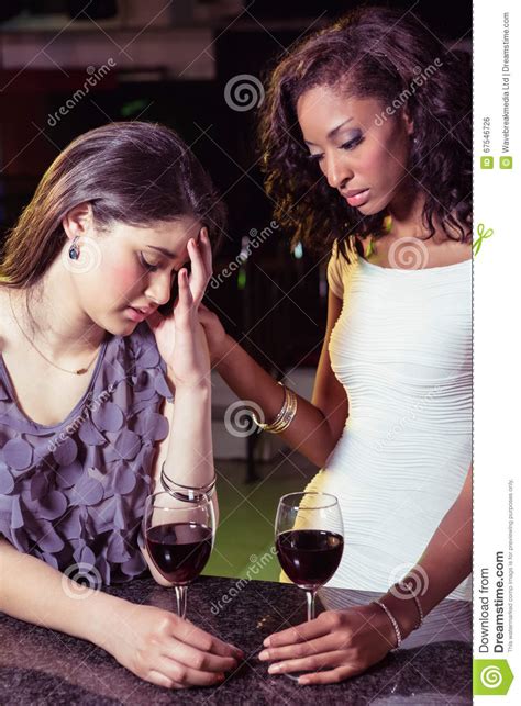 Woman Having Drinks And Comforting Her Depressed Friend Stock Photo