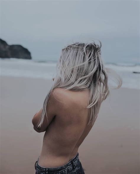A Nude Woman Standing On Top Of A Sandy Beach Next To The Ocean With
