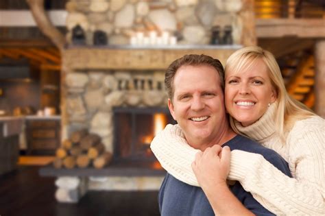 Happy Affectionate Couple At Rustic Fireplace In Log Cabin All