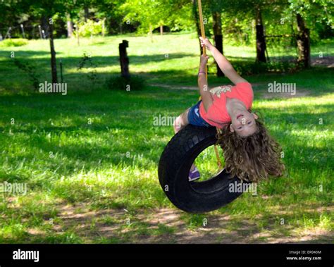 Young Elementary Aged Girl Swinging On A Tire Swing In The Bright