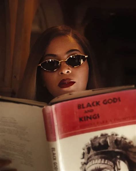 a woman wearing sunglasses reading a book with the title black god and king written on it