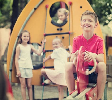 Smiling Boy Sitting On Swing On Children S Playground Stock Photo