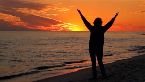 Woman Raises Her Hands In The Air To Worship And Pray At Sunset At The Seashore Stock Footage