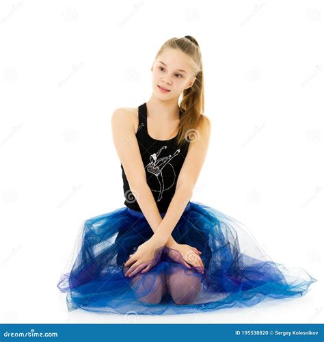 Blonde Girl In Stylish Tulle Dress Sitting On Floor Hugging Her Knees