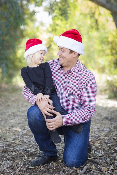 Retrato Del Padre Y De La Hija Que Llevan A Santa Hats Outdoors Imagen