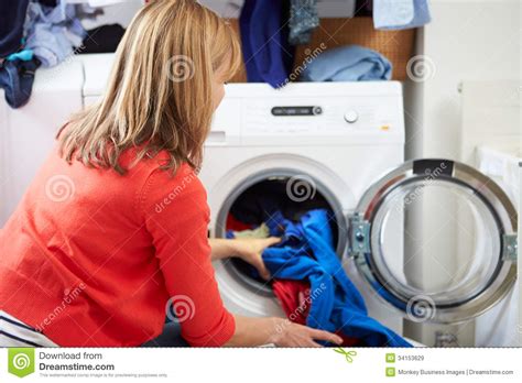 Woman Loading Clothes Into Washing Machine Stock Image