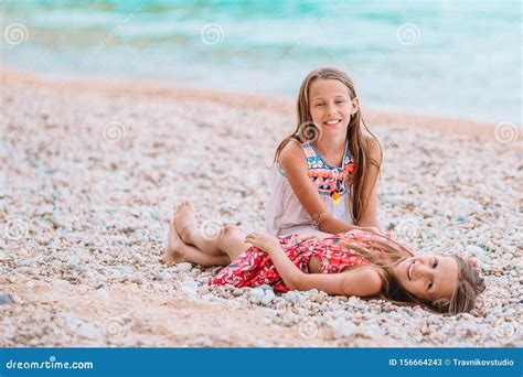 Two Little Happy Girls Have A Lot Of Fun At Tropical Beach Playing