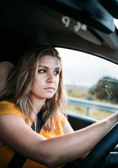 A Serious Young Woman Is Driving A Car Wearing A Seat Belt And Looking