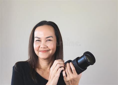 asian woman photographer holding dslr camera smiling and looking at camera isolated on white