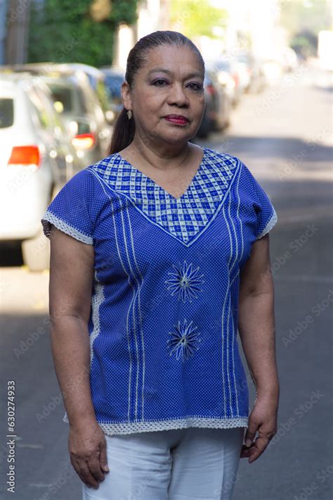mature mexican lady looking at the camera smiling wearing a traditional mexican embroidered