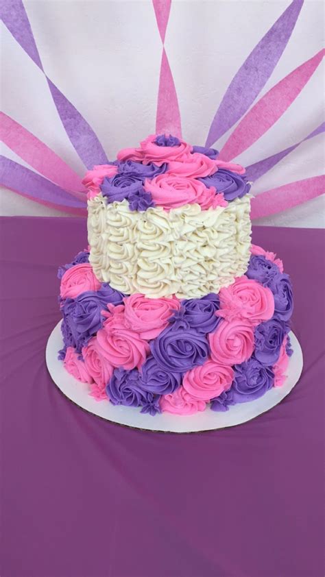 A Multi Colored Cake With Pink Purple And White Frosting On A Table