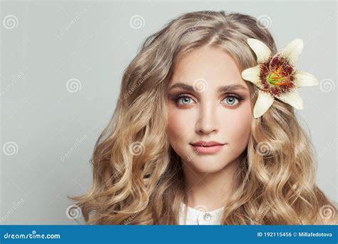 Cheerful Blonde Woman With Healthy Clear Skin And Flower In Long Curly