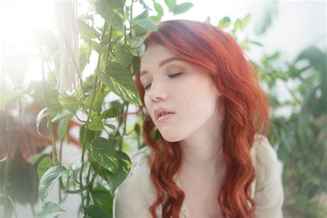 Tender Portrait Of A Young Beautiful Dreamy Redhead Woman Among Foliage